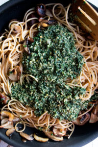 kale pesto being tossed with spaghetti