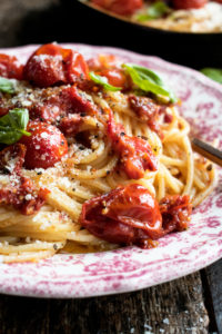Tomato Confit Spaghetti. A really simple summer pasta recipe that highlights sweet tomatoes in a rich & savory way. Topped with lots of parmesan and basil!