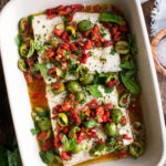 finished roasted halibut topped with red pepper and olive relish in a baking dish