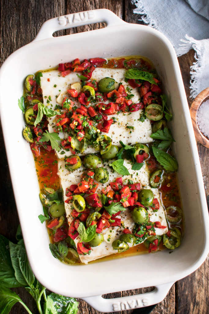 finished roasted halibut topped with red pepper and olive relish in a baking dish