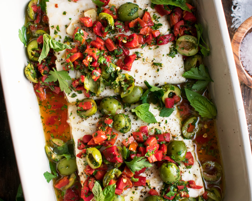 finished roasted halibut topped with red pepper and olive relish in a baking dish