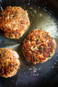 rye salmon cakes cooking in a skillet