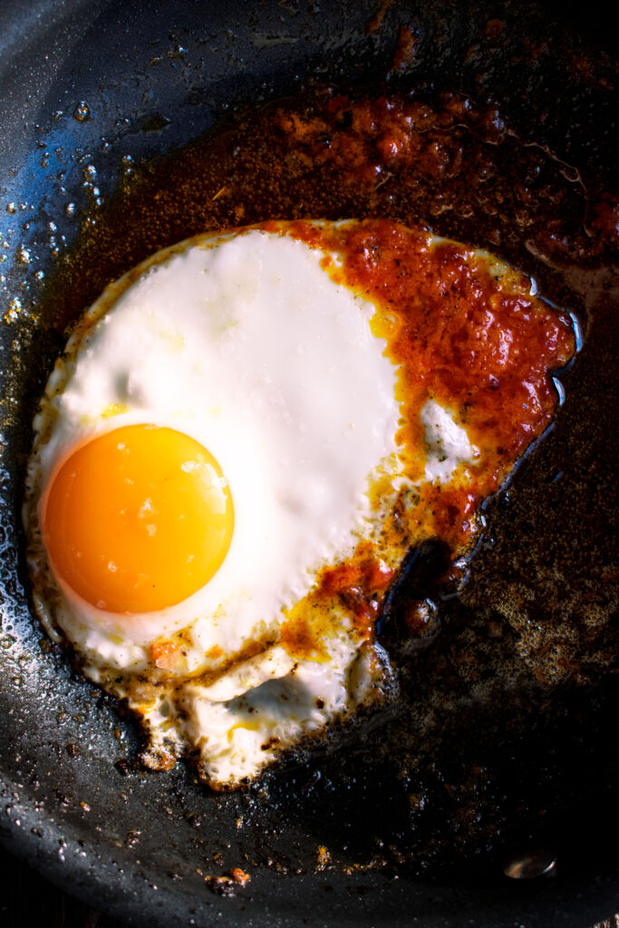 egg with spicy tomato butter frying in a skillet