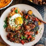 finished plate of roasted potato & sausage hash with fried eggs