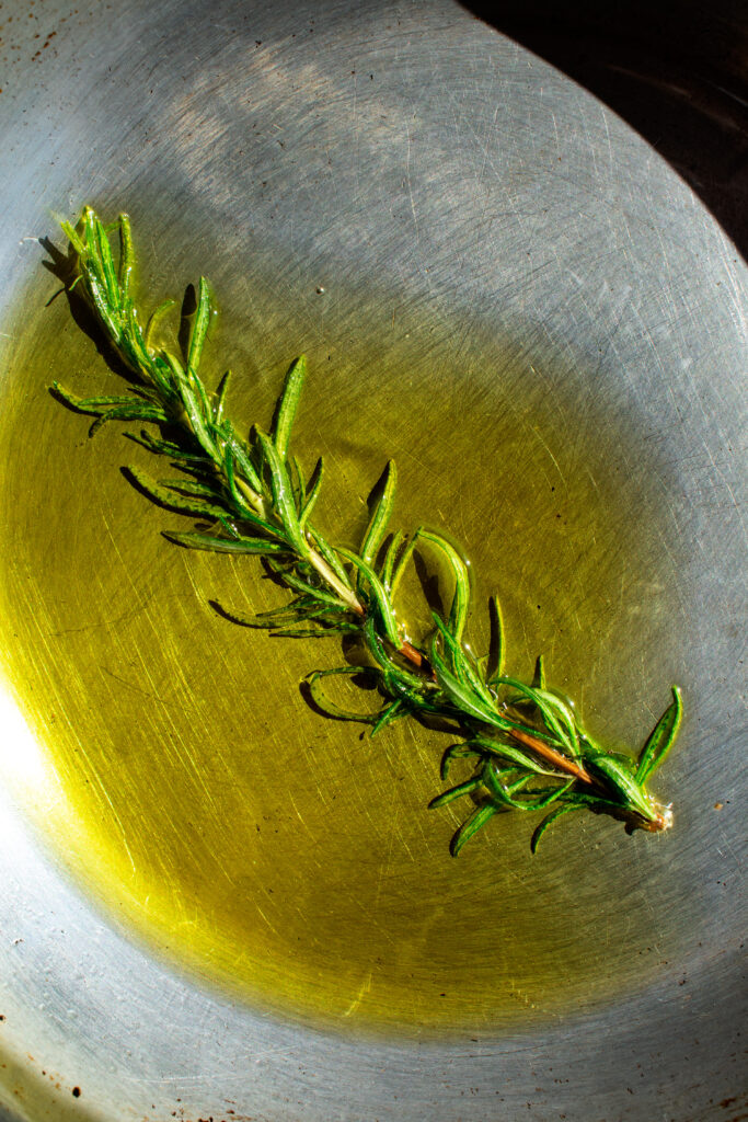 rosemary frying in a skillet of olive oil