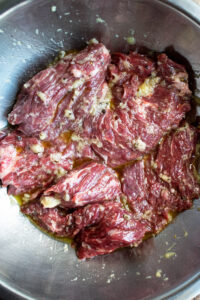 skirt steak marinating with olive oil and garlic in a bowl