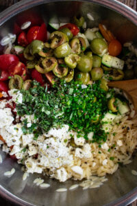 orzo salad ingredients in a mixing bowl