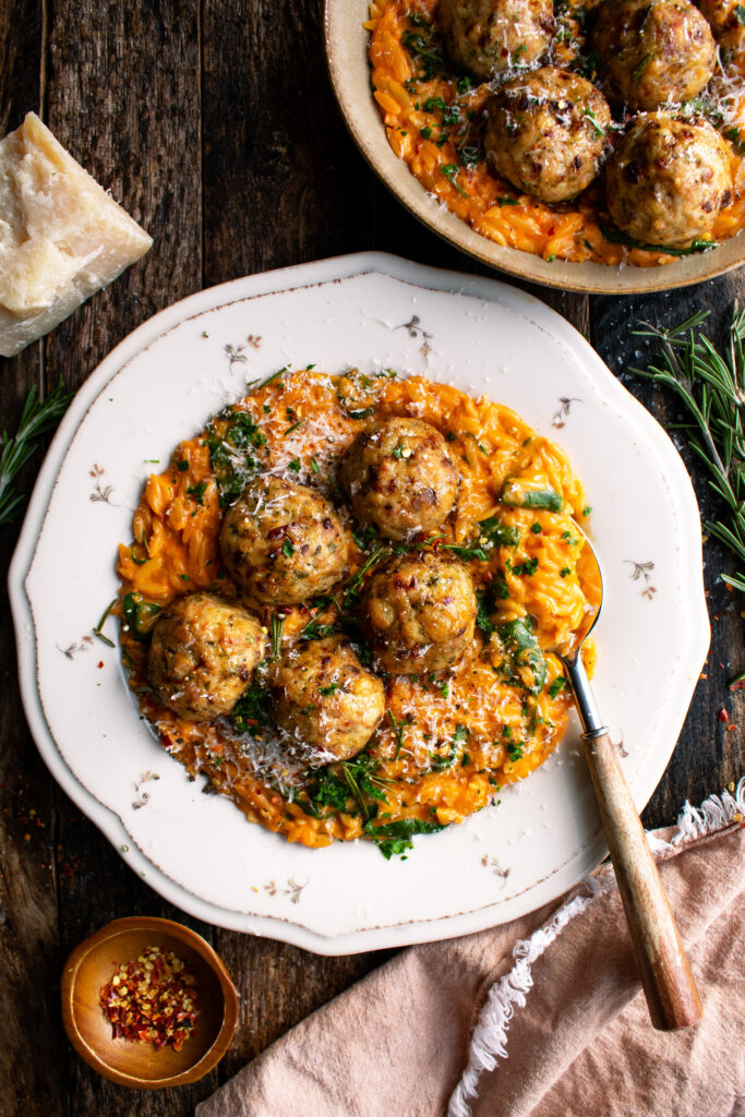 plate of Baked Rosemary Chicken Meatballs over tomato orzo