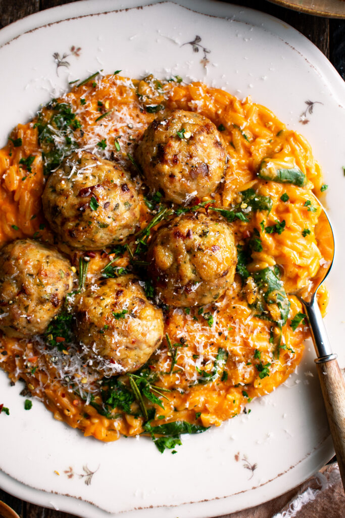 plate of Baked Rosemary Chicken Meatballs over tomato orzo