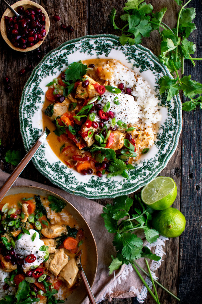 two bowls of Thai chicken curry served over rice with toppings