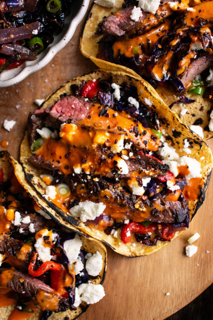 steak tacos with chipotle sauce & roasted cabbage slaw on a board