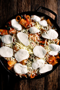 rigatoni in a skillet with mozzarella on top before baking