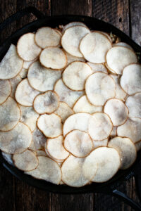 a skillet of layered potato slices during assembly