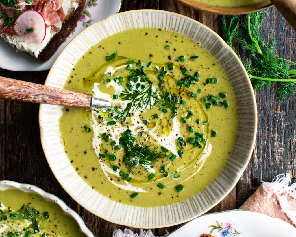 a bowl of Asparagus Soup topped with a drizzle of cream and fresh herbs