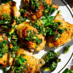 Crispy Chicken Thighs topped with charred green onion chimichurri on a plate