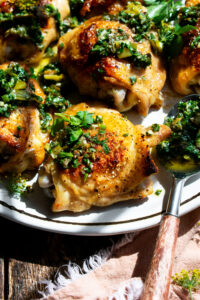 Crispy Chicken Thighs topped with charred green onion chimichurri on a plate