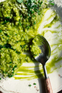 a plate of Spring Pea Risotto with a big spoon and spoonfuls of risotto eaten off the plate