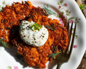two Sweet Potato Fritters on a plate with a dollop of dill yogurt sauce