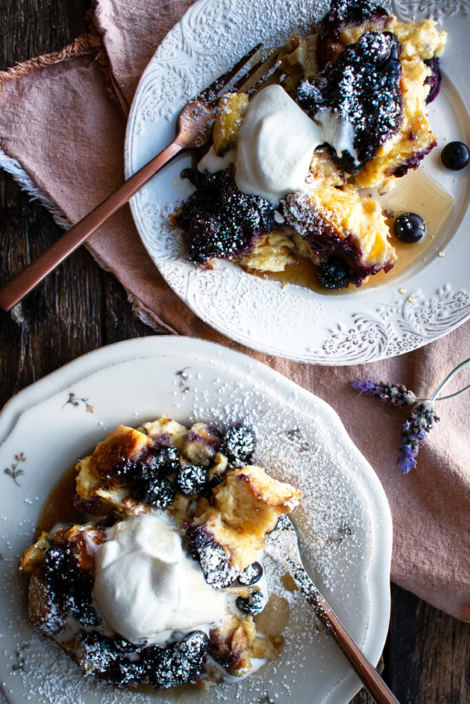 two plates of Baked Blueberry French Toast with whipped cream on top