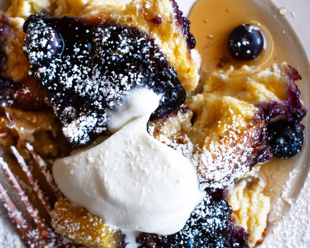 Baked Blueberry French Toast on a plate with a dollop of whipped cream on top