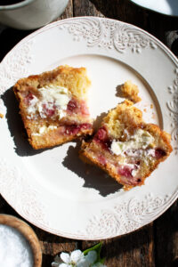 a slice of strawberry jam coffee cake with a smear of butter on a plate