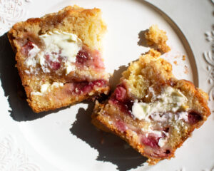a slice of strawberry jam coffee cake with a smear of butter on a plate