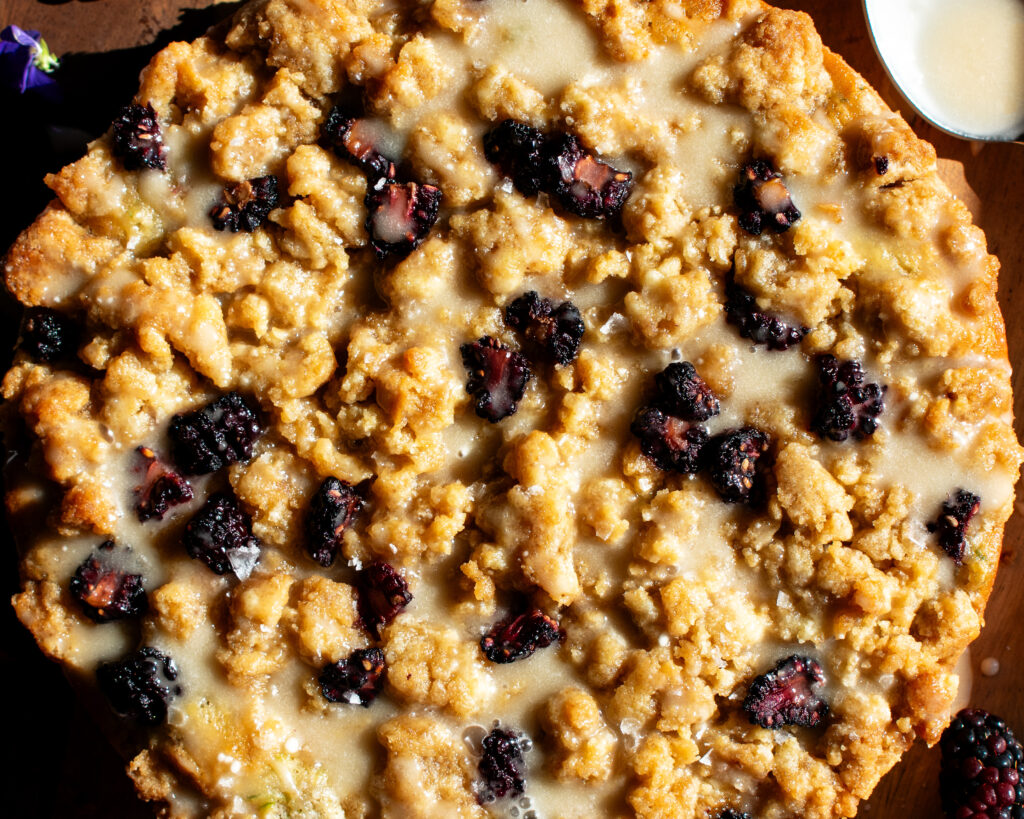 Blackberry Zucchini Coffee Cake on a board with honey glaze drizzled over top