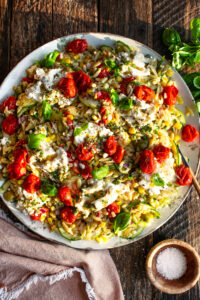 Orzo Salad with Roasted Tomato Vinaigrette on a serving platter with burrata cheese over top