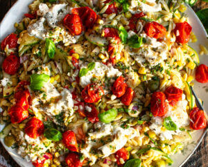 Orzo Salad with Roasted Tomato Vinaigrette on a serving platter with burrata cheese over top