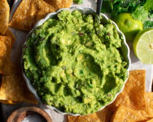 Homemade Guacamole in a bowl with tortilla chips on the side