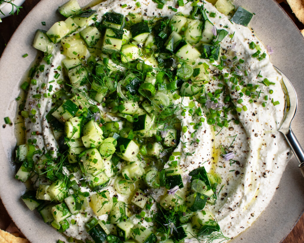 whipped feta dip on a plate with cucumber salad over top