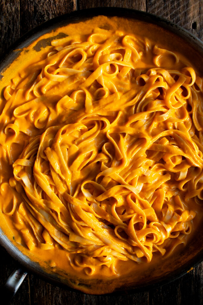 fettuccine in a pan tossed in the creamy tomato pasta sauce