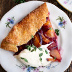 a slice of a Plum Galette topped with whipped mascarpone and fresh thyme
