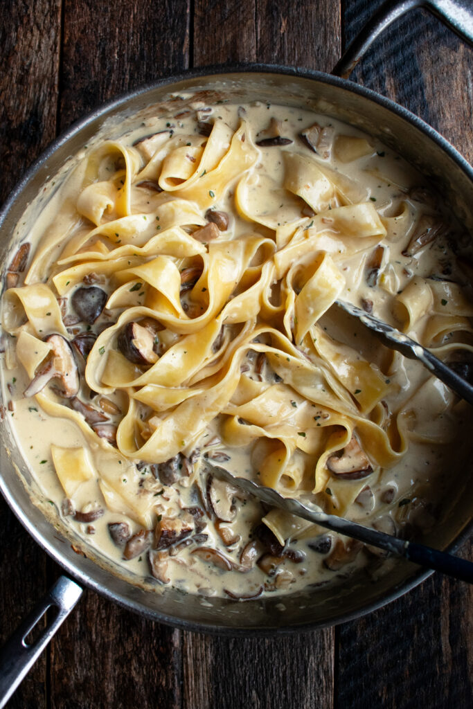 a pan of pappardelle pasta tossed in a creamy mushroom sauce