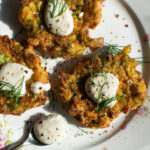 zucchini fritters on a plate with lemon yogurt sauce over top