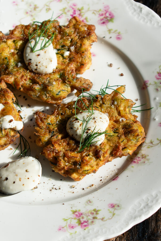 zucchini fritters on a plate with lemon yogurt sauce over top