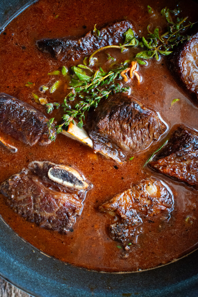 bone-in short ribs in a pot of braising liquid