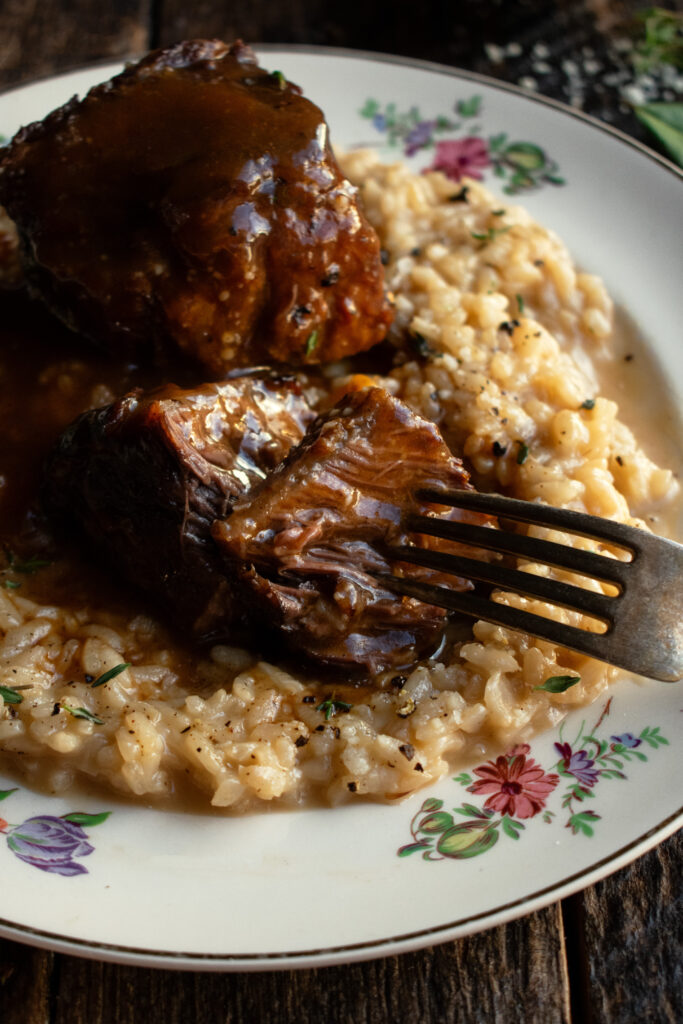 red wine braised short ribs over parmesan risotto on a plate