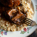 red wine braised short ribs over parmesan risotto on a plate