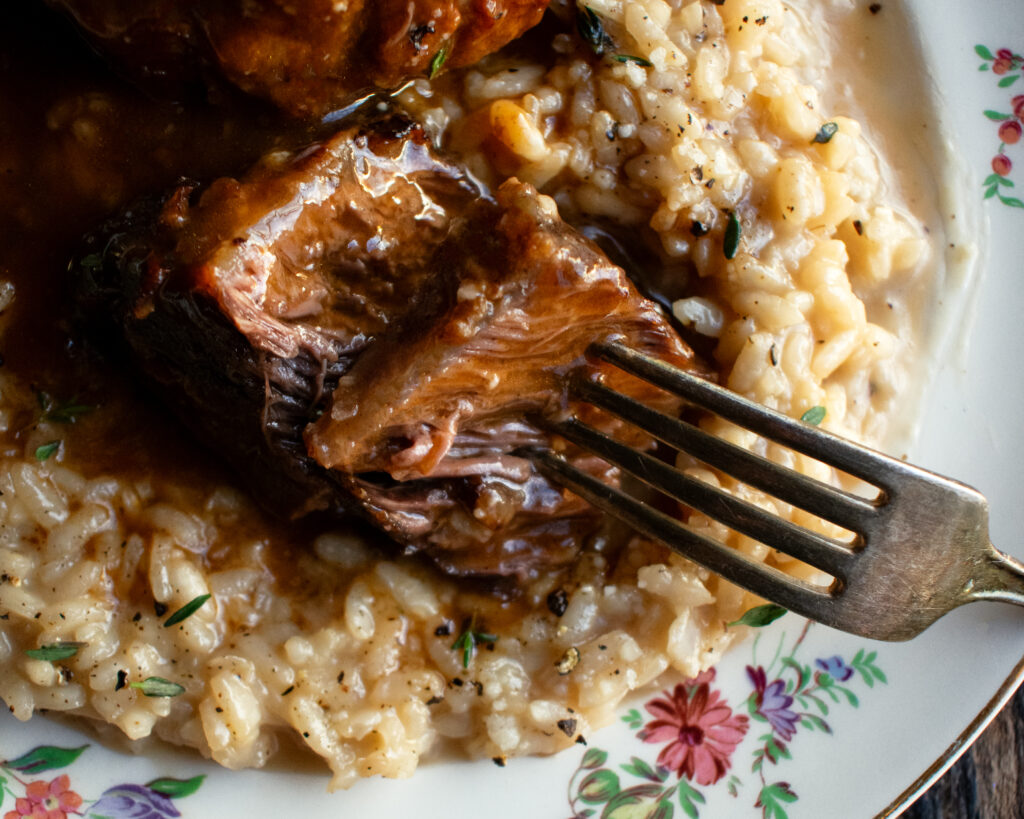 red wine braised short ribs over parmesan risotto on a plate
