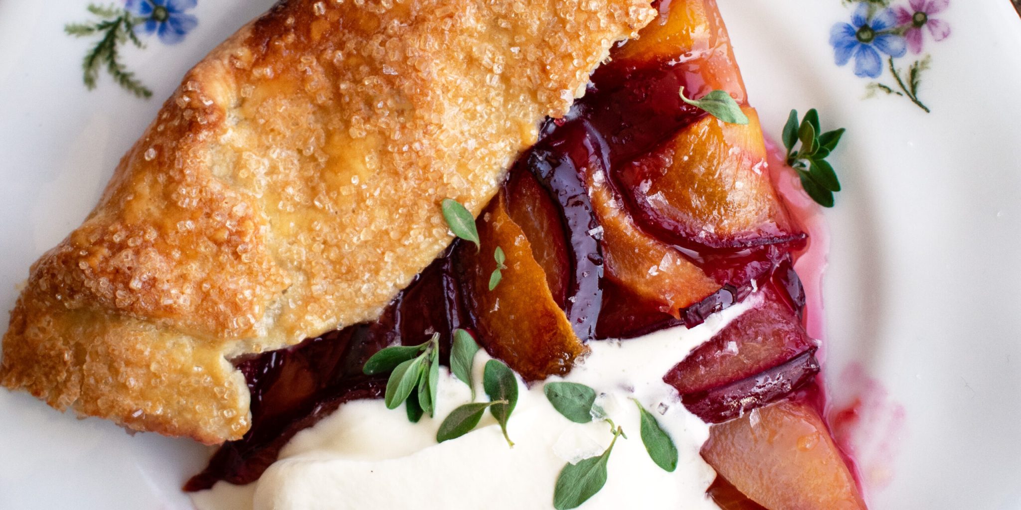 a slice of a Plum Galette topped with whipped mascarpone and fresh thyme